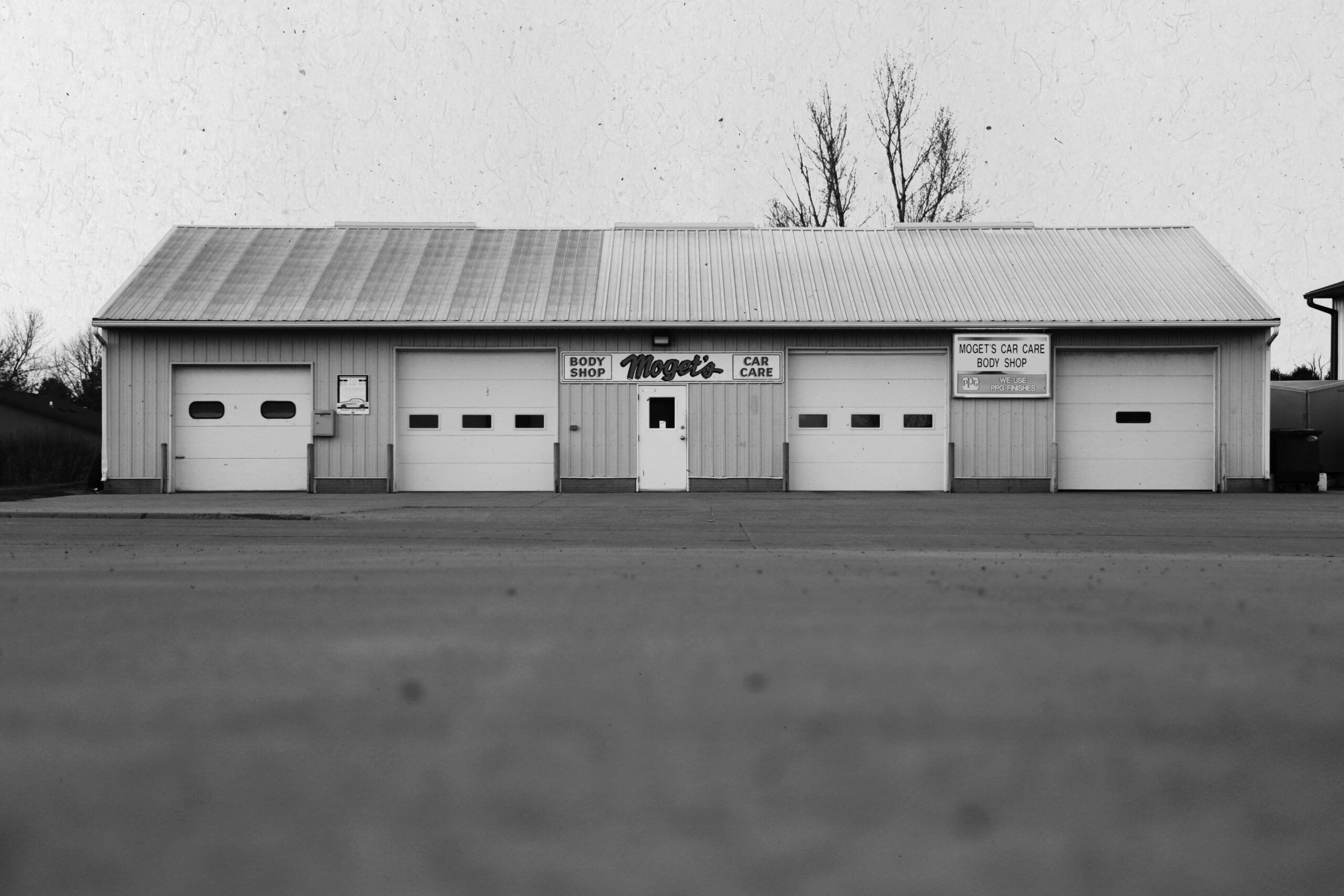 the building of Moget's Car care and body shop at low view and in black and white